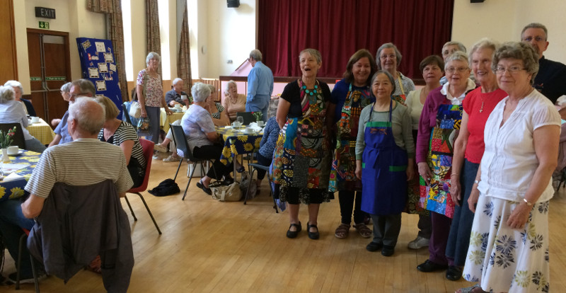 Members of Christ Church Southgate having lunch with the committee dressed in colourful Rwanda aprons Members of Christ Church Southgate having lunch with the committee dressed in colourful Rwanda aprons